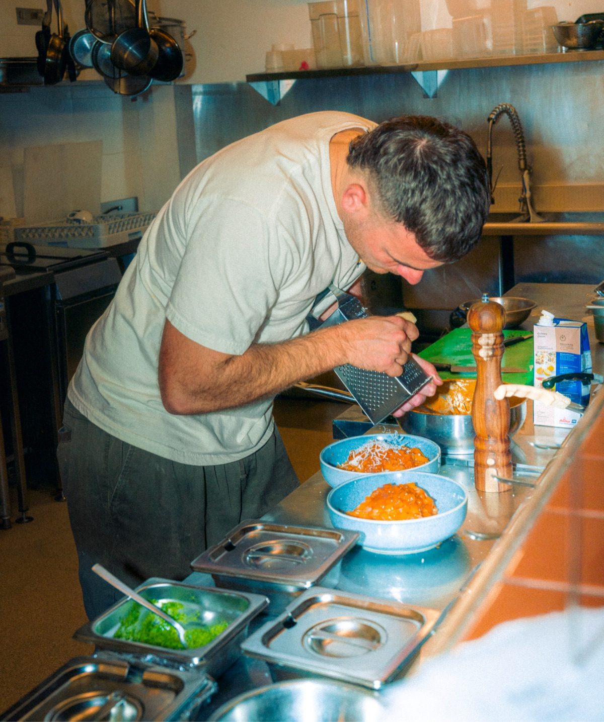 Chef grating pecorino over a bowl of fresh pasta